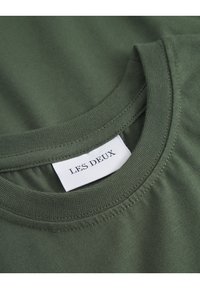 Olivno zeleni bombažni T-shirt z okroglo izreznico in šivi, z oznako "LES DEUX" vidno na oblačilu.