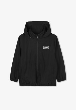 Veste légère noire avec capuche, poignets élastiques et ourlet, dotée d'une fermeture éclair à l'avant et d'un patch logo rectangulaire sur la poitrine gauche.