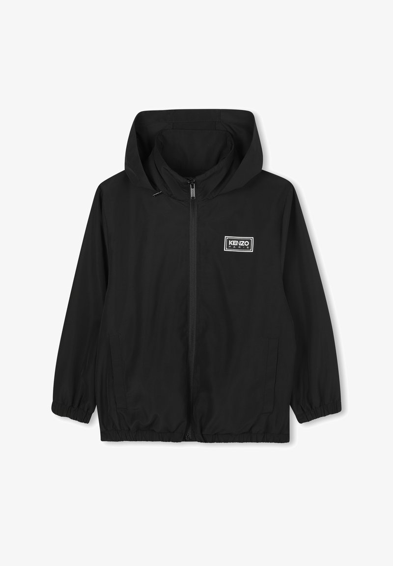 Veste légère noire avec capuche, poignets élastiques et ourlet, dotée d'une fermeture éclair à l'avant et d'un patch logo rectangulaire sur la poitrine gauche.