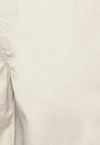 Light beige cotton fabric with a smooth texture and subtle sheen. Features minimal seams and stitching for a clean finish.