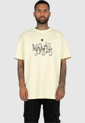 Light yellow cotton t-shirt with a relaxed fit, featuring a black graphic design in various fonts on the front. Short sleeves, crew neckline.