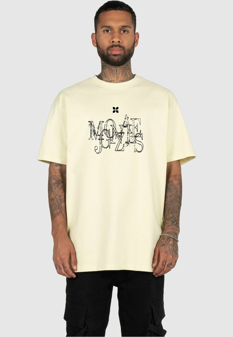 Light yellow cotton t-shirt with a relaxed fit, featuring a black graphic design in various fonts on the front. Short sleeves, crew neckline.
