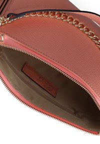 Interno di una borsa in pelle rosa con una fodera in tessuto marrone, dotato di un scomparto con cerniera e un'etichetta testurizzata. Hardware in ottone visibile lungo la cerniera.