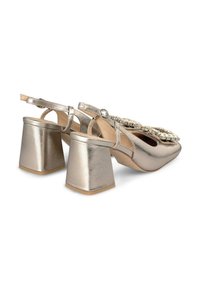 Chaussures slingback dorées métalliques avec une finition texturée, dotées d'un talon bloc et de décorations sur la zone des orteils.