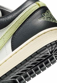 Czarny skórzany sneaker z jasnozielonymi akcentami, teksturowaną białą środkową podeszwą oraz szczegółowo wykonanym gumowym spodem. Wyróżnia się przeszyciami oraz logo.