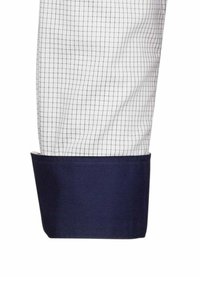 Tessuto della camicia bianca con un motivo a griglia nera; polsino blu navy con una texture liscia; design strutturato visibile all'estremità della manica.