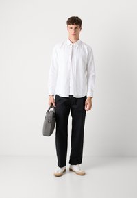 Witte overhemd met kraag, zwarte broek en grijze handtas. Witte schoenen met bruine zolen, minimalistisch ontwerp, gladde textuur.