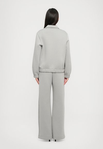 Grå sweatshirt med krave, ribbede manchetter og matchende brede sweatpants. Glat tekstur og afslappet pasform hele vejen igennem.