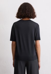 Schwarzer kurzärmliger Pullover mit lockerer Passform, aus glattem Material. Verfügt über einen runden Ausschnitt und einen Rippenbund, von hinten dargestellt.