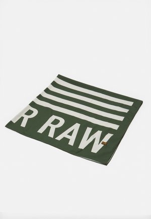 Tissu rectangulaire vert et blanc avec un texte en gras "R RAW" et des bandes horizontales, étalé à plat sur une surface blanche.