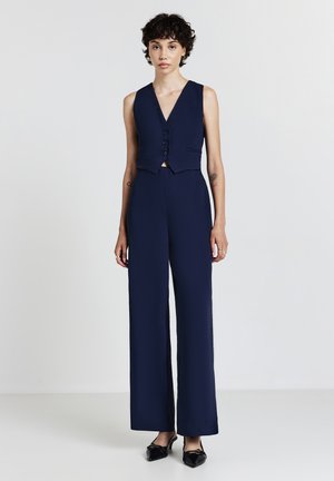 Tuta blu con top aderente e tre bottoni, pantaloni a gamba larga e tessuto liscia.