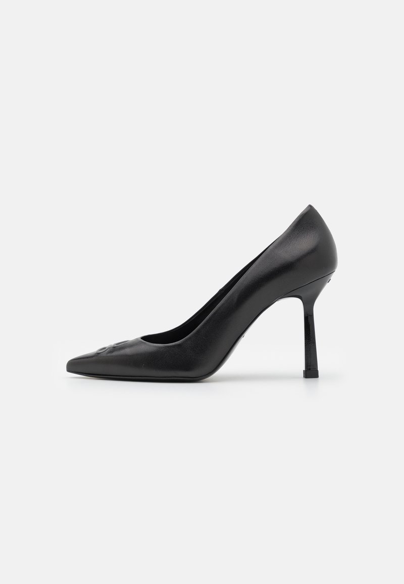 Chaussure à talon haut en cuir noir à bout pointu avec talon stiletto fin, montrée de profil sur un fond clair uni.