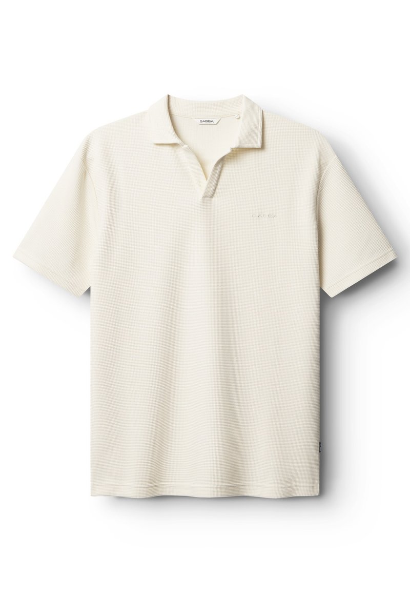 Polokošeľa svetlo krémovej farby, textúrovaná tkanina. Má golier, zapínanie na dva gombíky a nenápadné logo značky na ľavej strane hrudníka. Krátke rukávy.