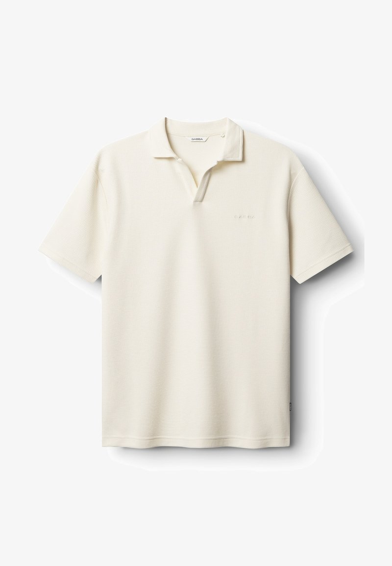 Polokošeľa svetlo krémovej farby, textúrovaná tkanina. Má golier, zapínanie na dva gombíky a nenápadné logo značky na ľavej strane hrudníka. Krátke rukávy.