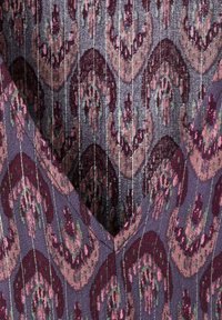 Textil cu un model tipărit în nuanțe de purpuriu închis, burgund și verde, cu o formă în V și linii verticale subtile pentru textură.
