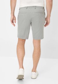 Pantaloni corti grigi con una superficie testurizzata, dotati di due tasche posteriori e un taglio sartoriale, abbinati a sneakers bianche.