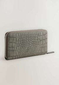 Grijze leren portemonnee met een krokodillenpatroon, voorzien van een zilveren rits en een platte tab voor gemakkelijk openen, gemaakt van duurzaam materiaal.