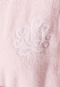 Tessuto in spugna rosa chiaro con una struttura morbida. Presenta le iniziali ricamate in bianco "RL" in un design corsivo.