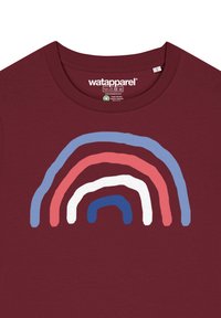 Bordeaux t-shirt met een grafiek van vijf overlappende regenboogbogen in blauw, wit, roze en rood. Zacht materiaal en ontwerp met ronde hals.
