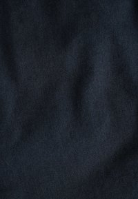 Tissu en denim foncé au toucher lisse, présentant un motif de tissage en sergé distinct et des variations de couleur subtiles.