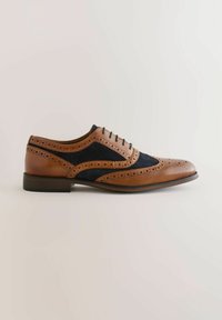 Pruunist nahast ja tumesinist sametist brogue-kontsaga king, millel on dekoratiivsed perforatsioonid, paeltega sulgemine ja madal virnastatud konts. Klassikaline wingtip-kuju.