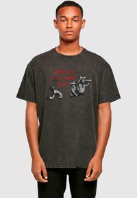 Musthave suur must puuvillane T-särk, millel on graafika kolme figuuriga ja punane tekst "OLEME KÕIK SAMAS PAATIS." Kulunud tekstuur.
