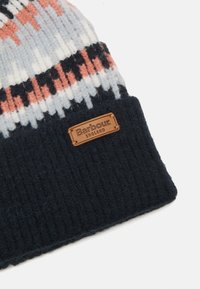 Knitted beanie hat in grey, white, and coral patterns, with a dark navy ribbed band. Features a brown leather label with "Barbour" and "England."