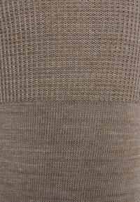 Tejido acanalado en tonos de beige, con un patrón texturizado. El material tiene un aspecto suave y de punto, con un acabado liso.