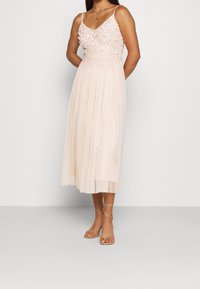 Blush-pink Midi-Kleid mit einem taillierten, verzierten Oberteil und einem durchsichtigen, plissierten Rock. Verstellbare Träger und zarte Sandalen runden den Look ab.