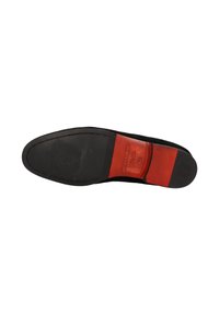 Suela de zapato negra con un patrón texturizado; cuenta con un acento de cuero rojo y un logo embosado, bordes suaves y una base plana.
