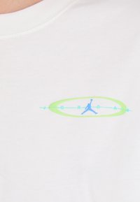 Weißes Baumwoll-T-Shirt mit einem blauen und grünen Grafiklogo in der Mitte, das den Text "JORDAN" und die Silhouette einer springenden Figur zeigt.