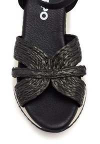 Sandal negra con tiras trenzadas de material texturizado, plantilla acolchada negra y suela blanca texturizada.