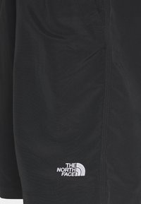 Pantaloni corti neri in tessuto liscio con orlo cucito e un logo ricamato bianco di The North Face sul lato sinistro.