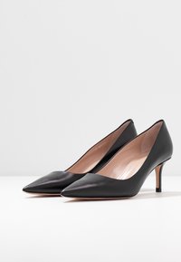 Décolleté nere in pelle con punta affusolata e una leggera lucentezza, tacco medio e interno liscio. Presentano un design classico, ideale per abbigliamento formale.