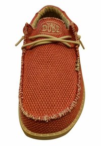 Röd vävd tygsko med beige snören och sömmar. Sålen är ljusbrun med ett texturerat mönster. "HEY DUDE"-logotyp på tungan.