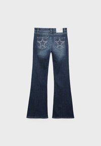 Ciemnoniebieskie dzwony dżinsowe widziane od tyłu, z dwoma kieszeniami ozdobionymi dużymi gwiazdami wyszywanymi na nich.