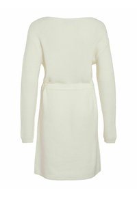 Mekana bijela pletena odjeća dugih rukava, s pojasom u struku i bočnim prorezima. Teksturirani materijal stvara udoban izgled i dojam.