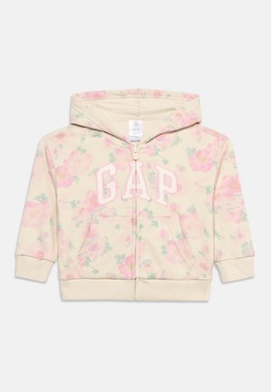 Lasten vetoketjullinen huppari, jossa on vaaleanpunainen kukkakuvio ja etutaskut. Edessä suuri "GAP"-logo vaaleanpunaisilla kirjaimilla rinnassa.