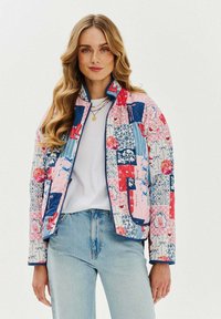 Prošívaná bunda s patchworkovým designem v růžové, modré a červené barvě s květinovými a geometrickými vzory, s zipovým zapínáním a bočními kapsami.
