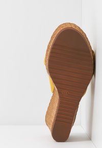 Semelle d’une sandale compensée jaune avec semelle en caoutchouc marron texturée et talon compensé tissé style espadrille, taille 37 marquée sous la semelle.