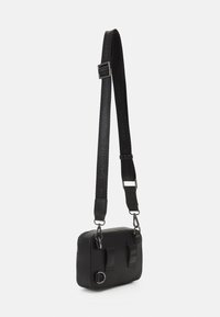 Borsa a tracolla rettangolare nera realizzata in pelle texturizzata. Presenta due cinturini frontali, una chiusura con zip e una tracolla con logo regolabile.
