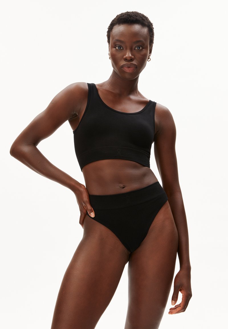 Zwarte naadloze cropped top en hooggetailleerde slip in een geribbelde textuur. De stof is glad, met een aansluitende silhouet en minimale ontwerpdetails.