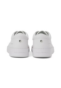 Fehér bőr tornacipő sima felülettel, lekerekített hátsó résszel, vastag talppal és fém logóval a saroknál. Letisztult és minimalista dizájn.