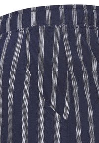 Navy blue fabric with white vertical stripes. Features an elastic waistband and a side pocket. Soft texture with a lightweight design.