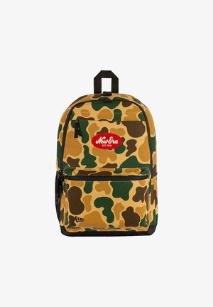 Sac à dos avec motif camouflage vert, marron et beige, poche avant zippée, poignée noire et patch ovale rouge avec le logo "New Era".