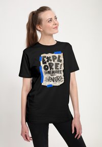 Sort t-shirt med et krøllet note-graphic med teksten "UTFORSK! NOGEN FLERE EVENTYR" tape med blå accenter.