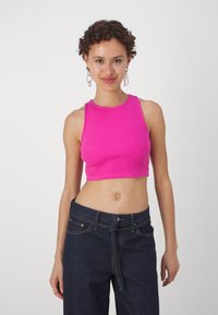 Fuksia ribbade kortärmade topp med rundad halsringning och breda axelband, i kombination med mörk denimbyxor med hög midja.