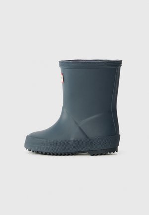 Une seule botte de pluie en caoutchouc bleu foncé avec une semelle texturée et une petite étiquette rectangulaire sur la partie supérieure avant.