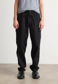 Pantalons cargo noirs avec une coupe décontractée, dotés de poches latérales et d'une taille élastique. Fabriqués en tissu durable avec une texture lisse.