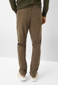 Bruine katoenen broek met een slim fit, voorzien van twee achterzakken en een gladde textuur. Gecombineerd met crèmekleurige schoenen voor contrast.